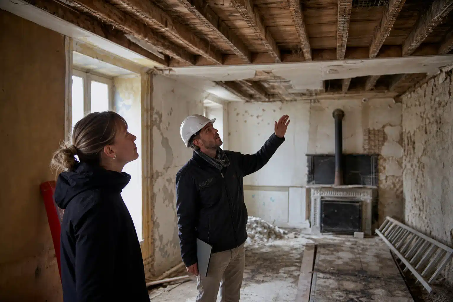 Homme en casque et femme inspectant plafond délabré